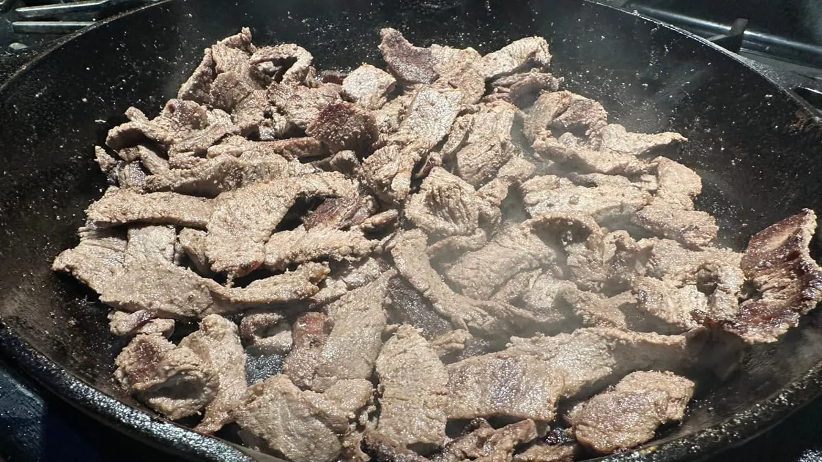 The sirloin browned through, steaming in the cast iron skillet