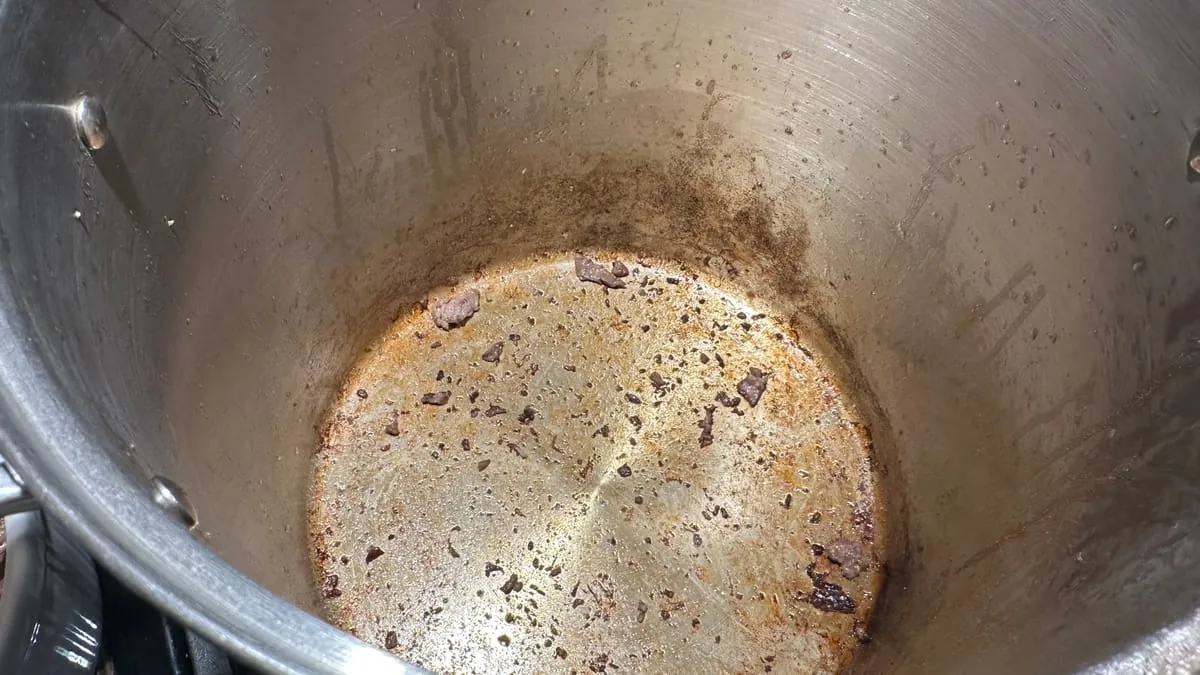The bottom of the pot after the beef comes out, glazed brown with stuck-on bits